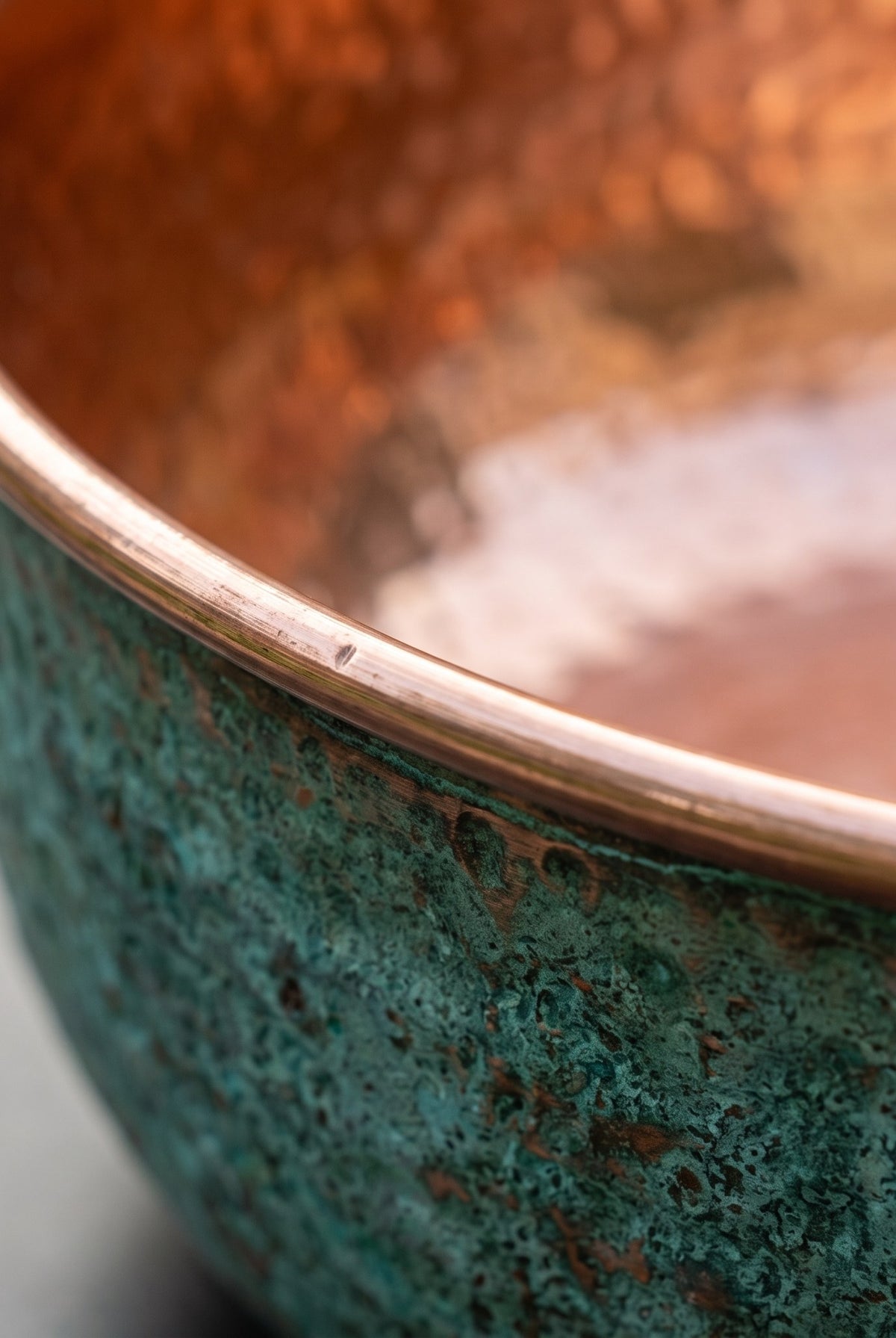 Close detail of the rim where the green patina meets the polished copper lining