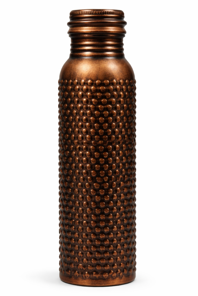 Detailed close-up of the intricate floral embossed patterns on an antique copper bottle.