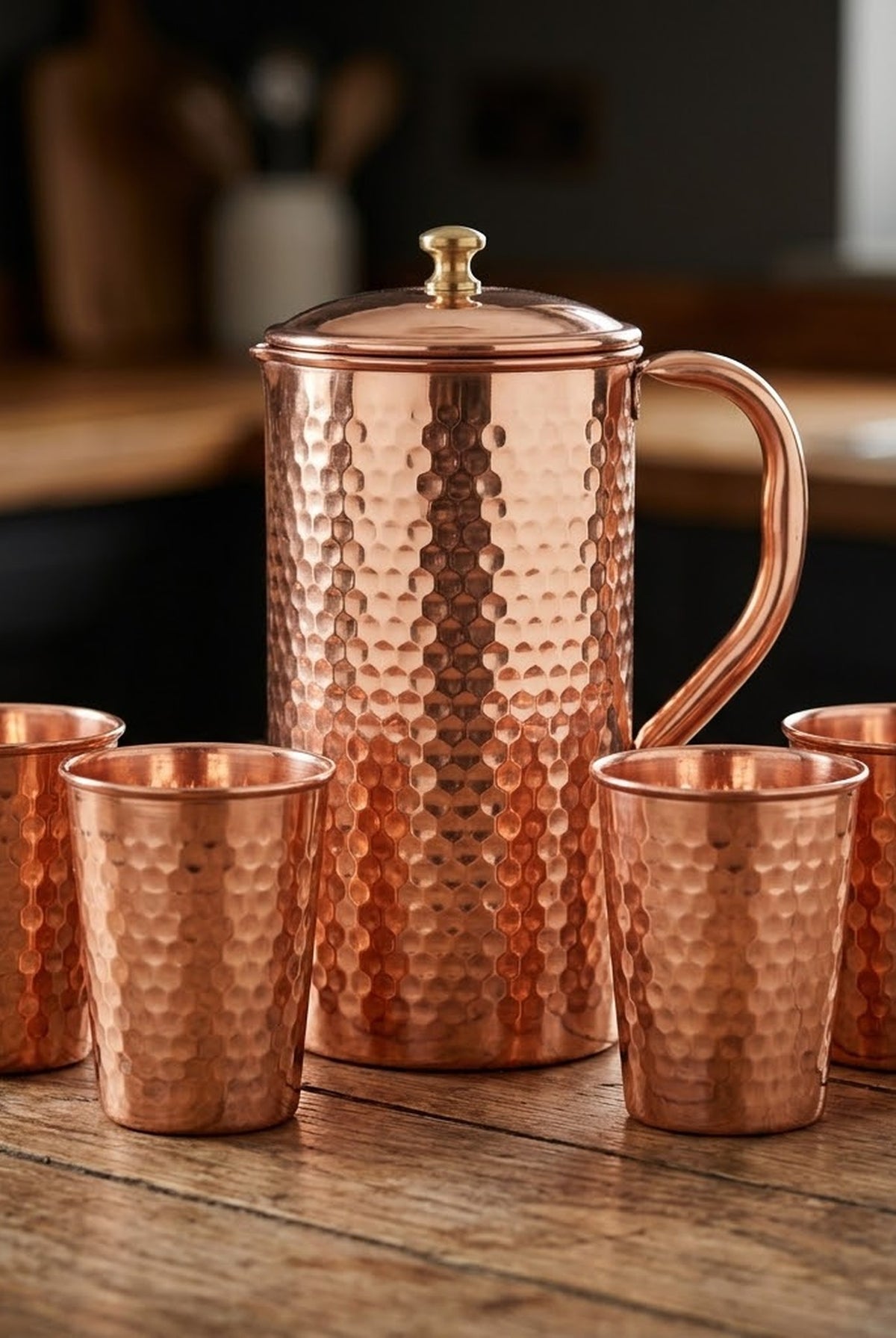 Hand hammered copper jug and four matching copper glasses from the 1.5L set, on a timber table