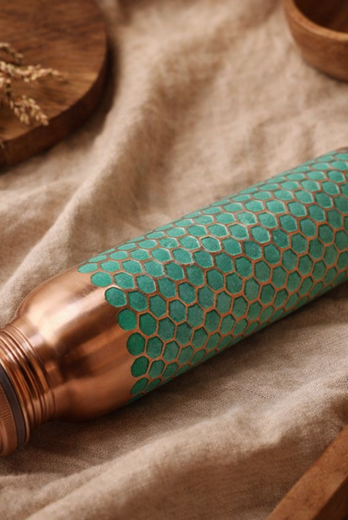 Luxury copper water bottle with a textured green finish on a wooden table