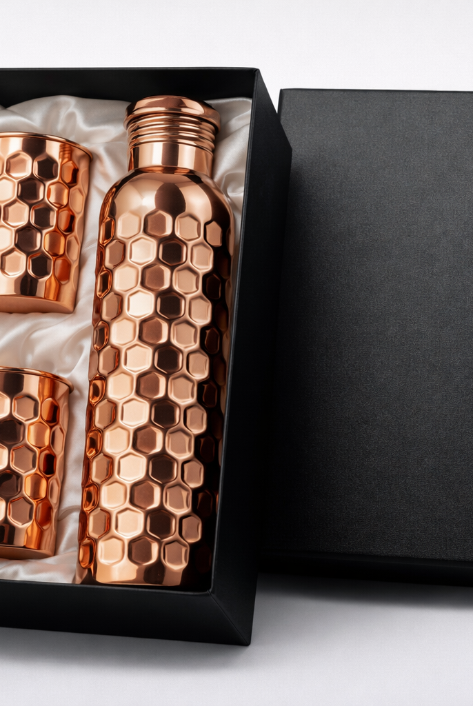Close-up of a hand-crafted embossed copper bottle and matching glass set