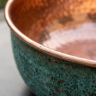 Close detail of the rim where the green patina meets the polished copper lining