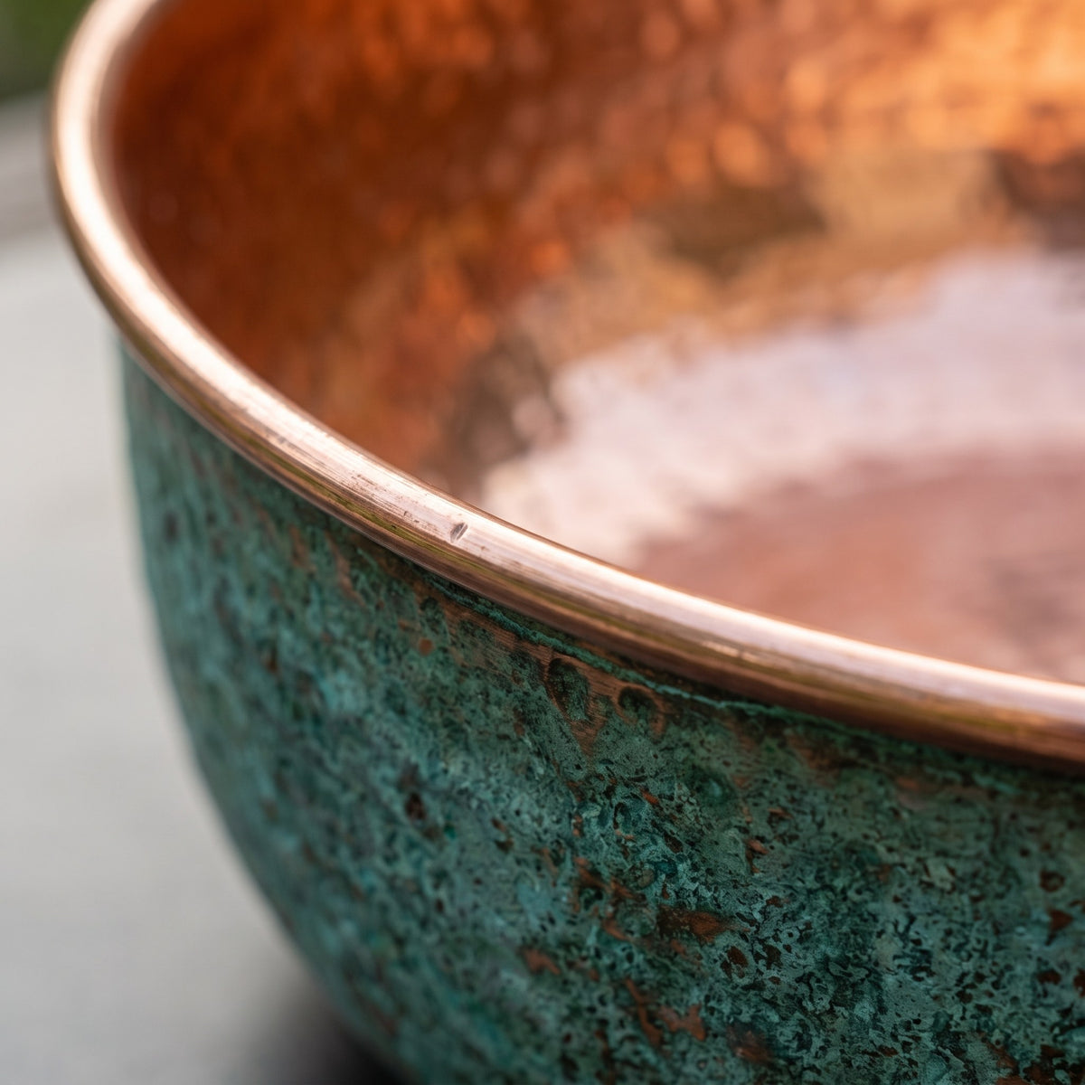 Close detail of the rim where the green patina meets the polished copper lining
