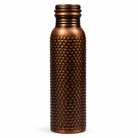 Detailed close-up of the intricate floral embossed patterns on an antique copper bottle.