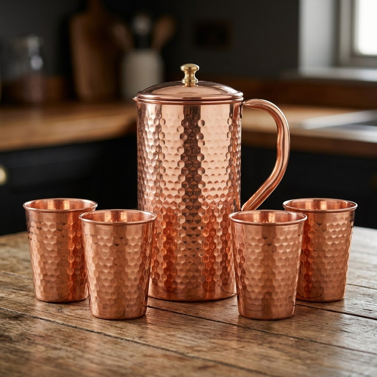 Hand hammered copper jug and four matching copper glasses from the 1.5L set, on a timber table