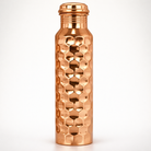 Close-up of the intricate hand-embossed design on a shiny copper bottle.