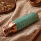 Luxury copper water bottle with a textured green finish on a wooden table
